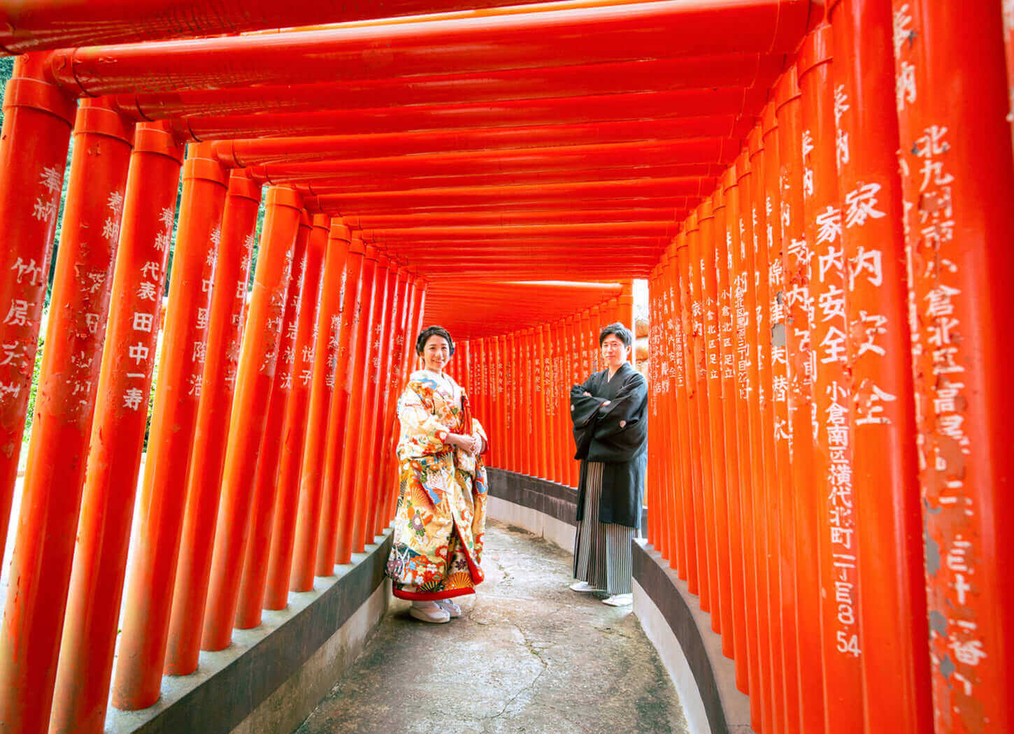 ウエディングドレスと和装の新郎新婦、フォトウエディング北九州の鮮やかな鳥居の中でのロケ撮影