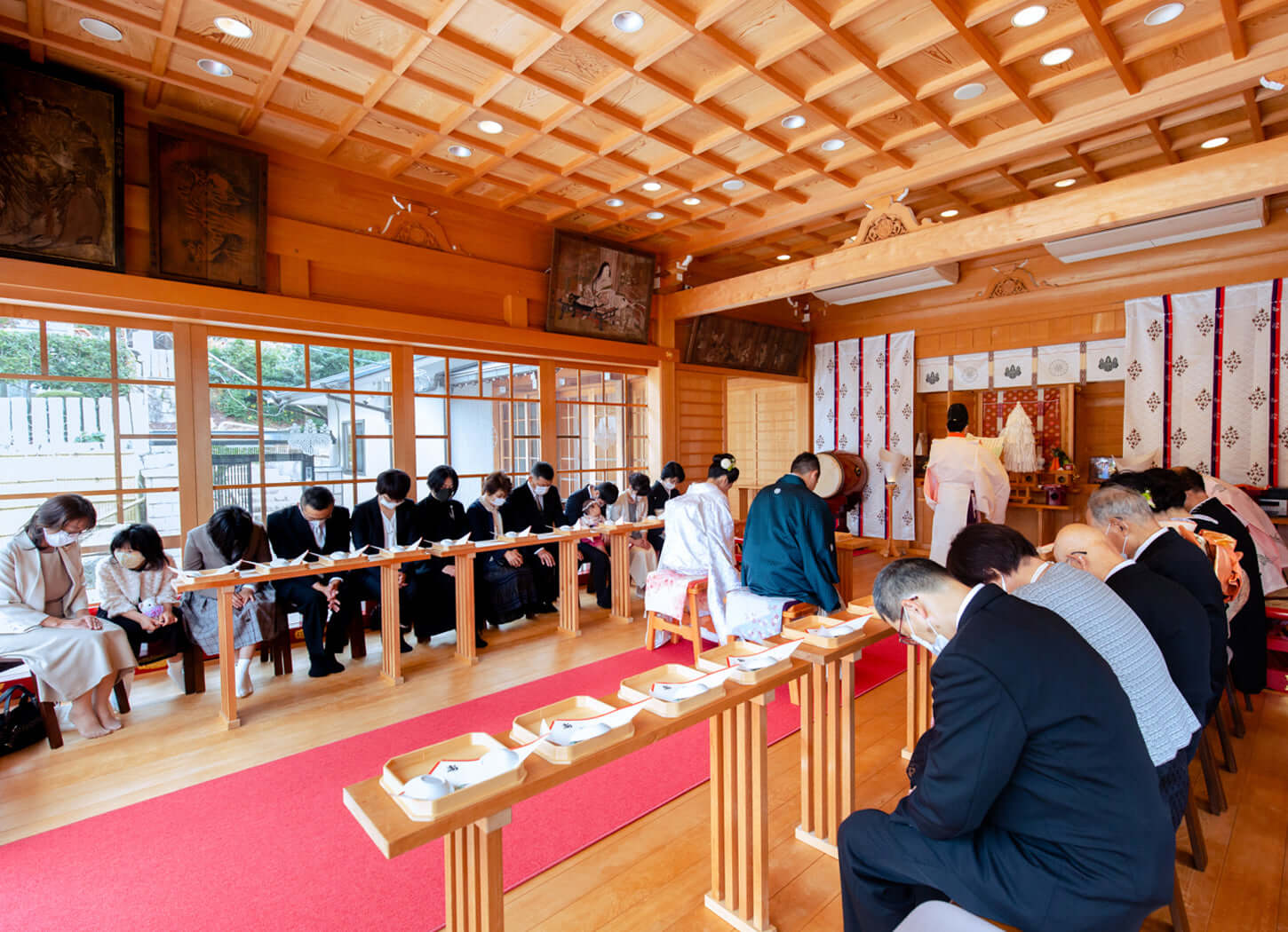 神社での挙式中、参列者が厳かに座り、和装の新郎新婦が式を執り行うシーン。フォトウエディング北九州