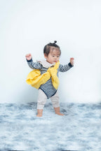 1歳のお誕生日を祝う子供の写真、ストライプの服を着て黄色い布を持つ幼児