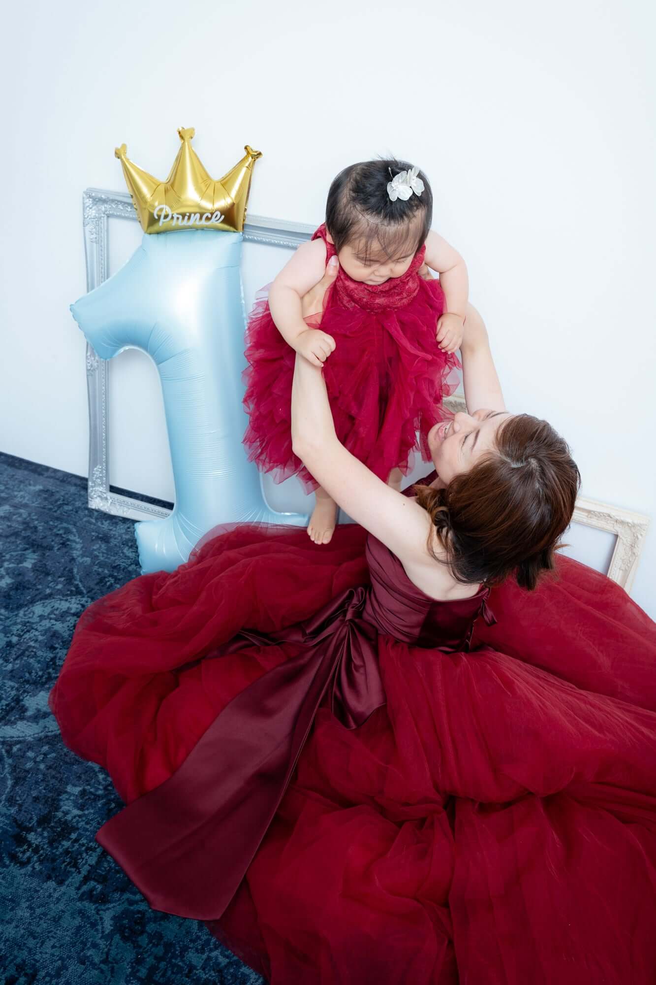 親子コーデフォト、お子様の誕生日を祝うママと赤いドレスの女の子の素敵な瞬間。