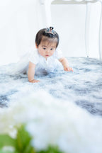 1歳のお祝いに白いドレスを着た赤ちゃんがじっと見つめる様子