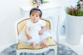 1歳の女の子が白いドレスを着て椅子に座っている可愛い写真