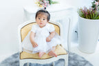 1歳の女の子が白いドレスを着て椅子に座っている可愛い写真