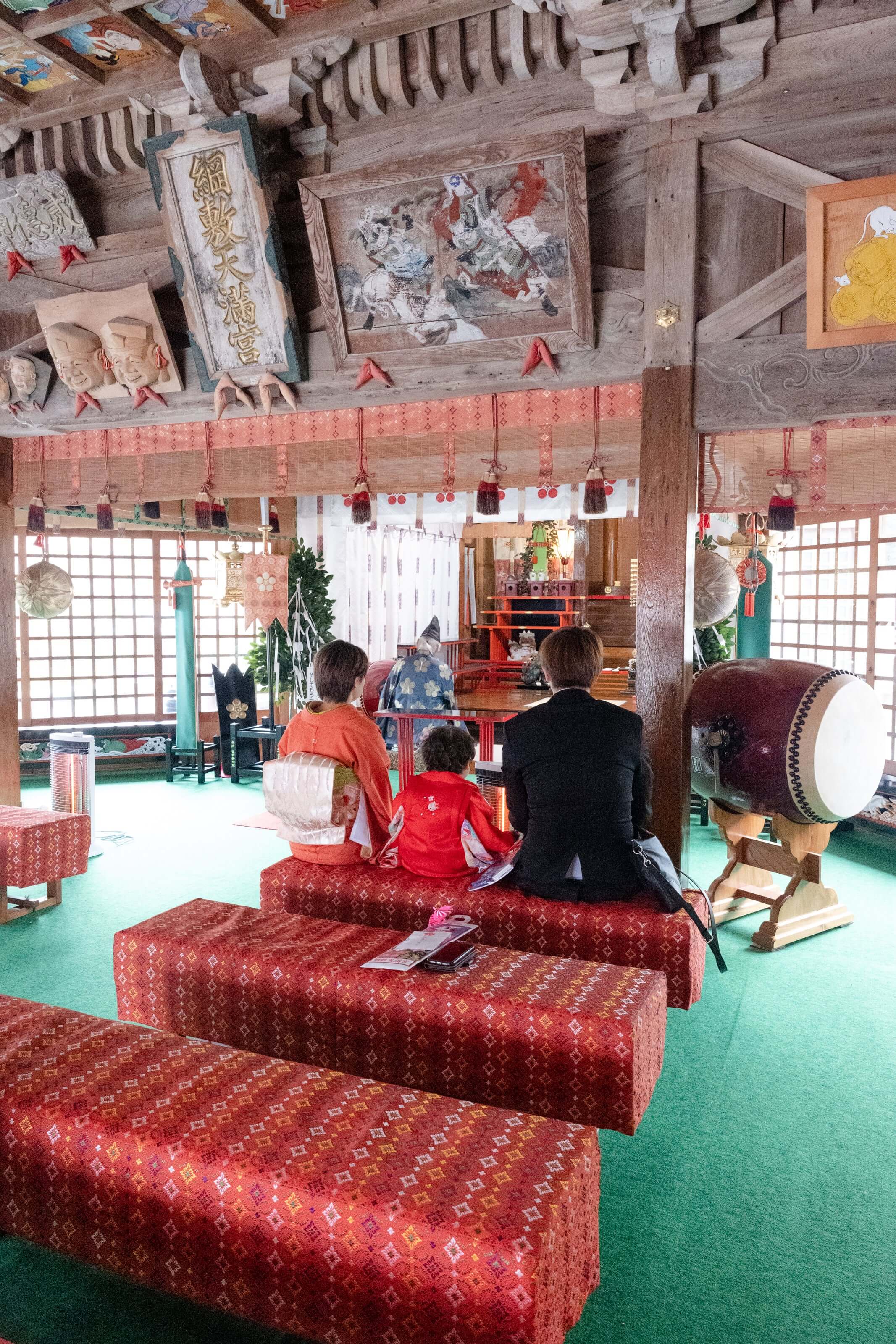 七五三の祝いを受ける子どもたちが神社内で座っている様子。フォトウエディング北九州。