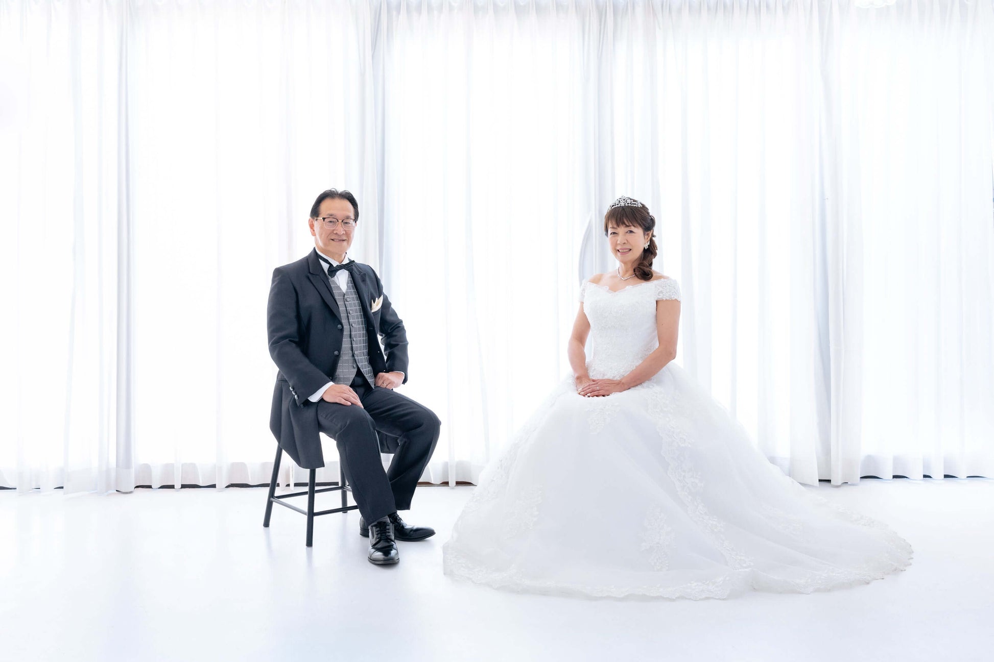 新郎新婦が純白のスタジオでポーズをとるフォトウエディングの結婚写真。