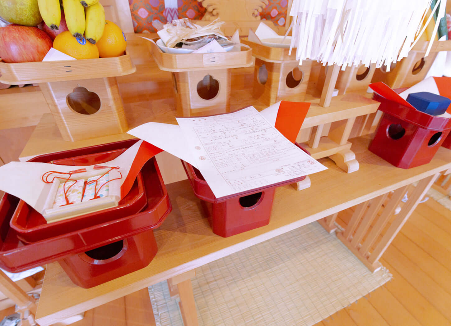 神社での儀式用の赤い神前道具と書類が置かれたテーブルの画像