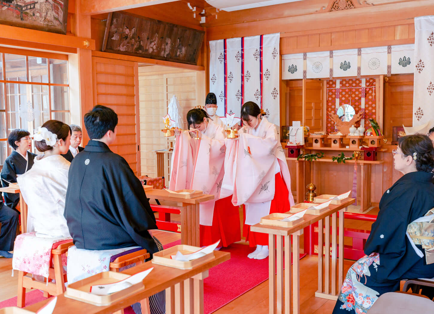 神社挙式のシーン、白無垢と袴の男女が神社内で祈りを捧げる様子。北九州のフォトウエディング。