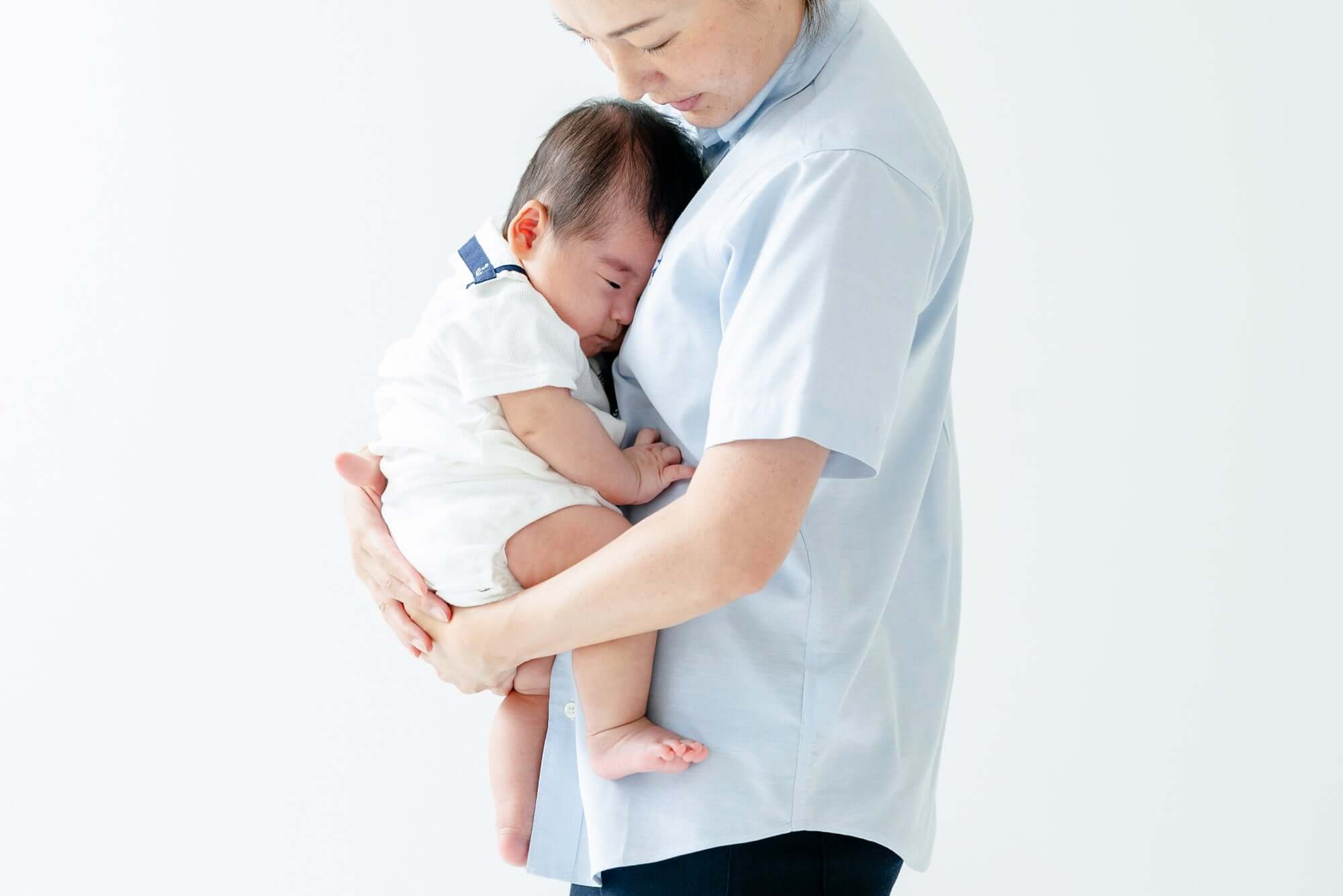 母親が赤ちゃんを抱くお宮参りシーン、フォトウエディング北九州の撮影。