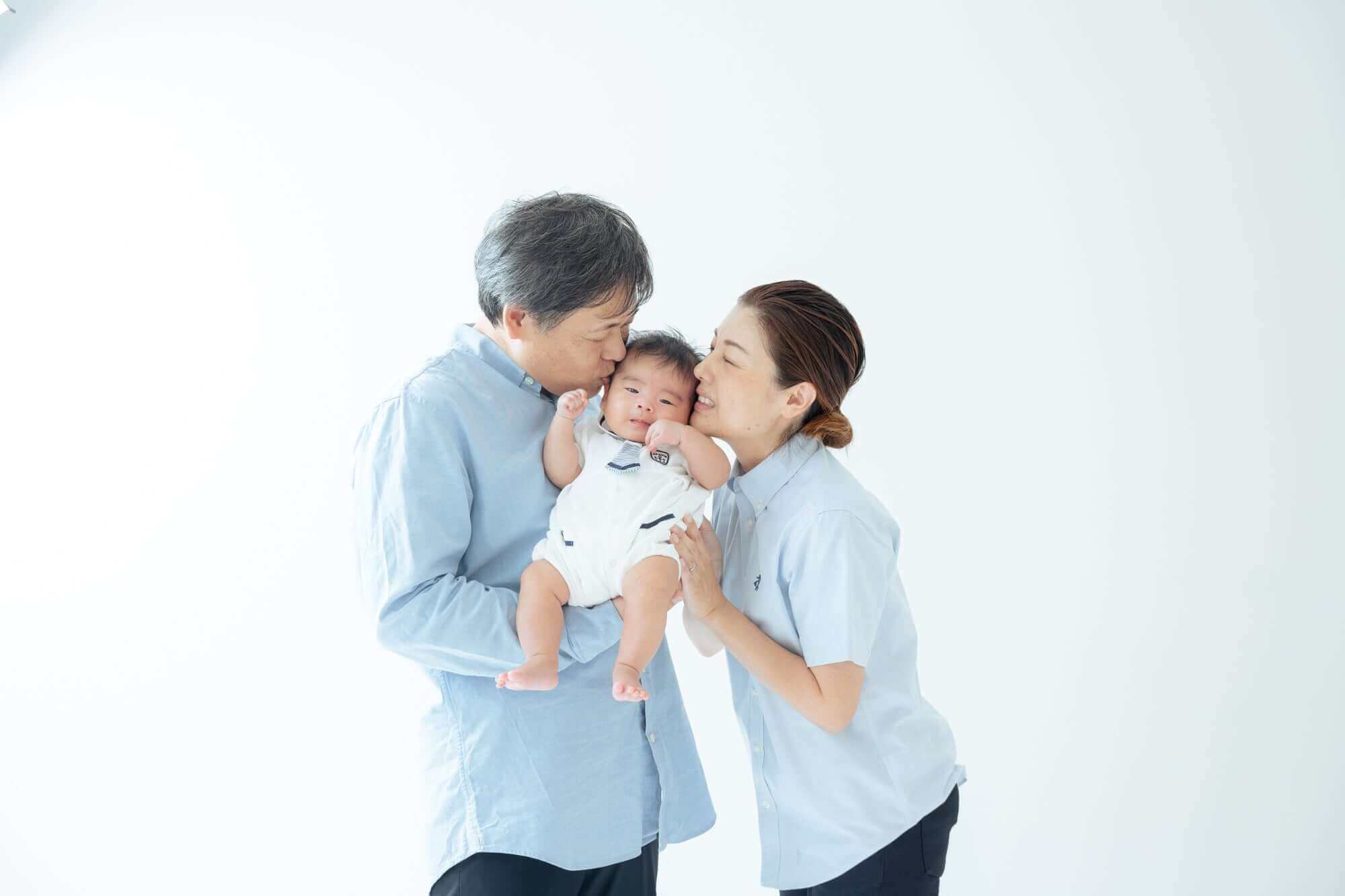 家族の愛情を表現するお宮参りの写真。赤ちゃんを抱く両親が幸せを感じる瞬間。フォトウエディング北九州。