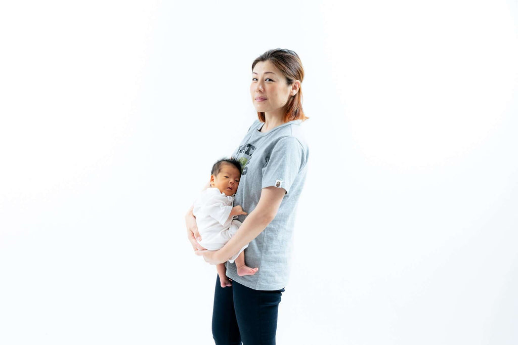 母親と赤ちゃんの親子コーデ写真、明るい背景で自然なポーズを取るシーン。