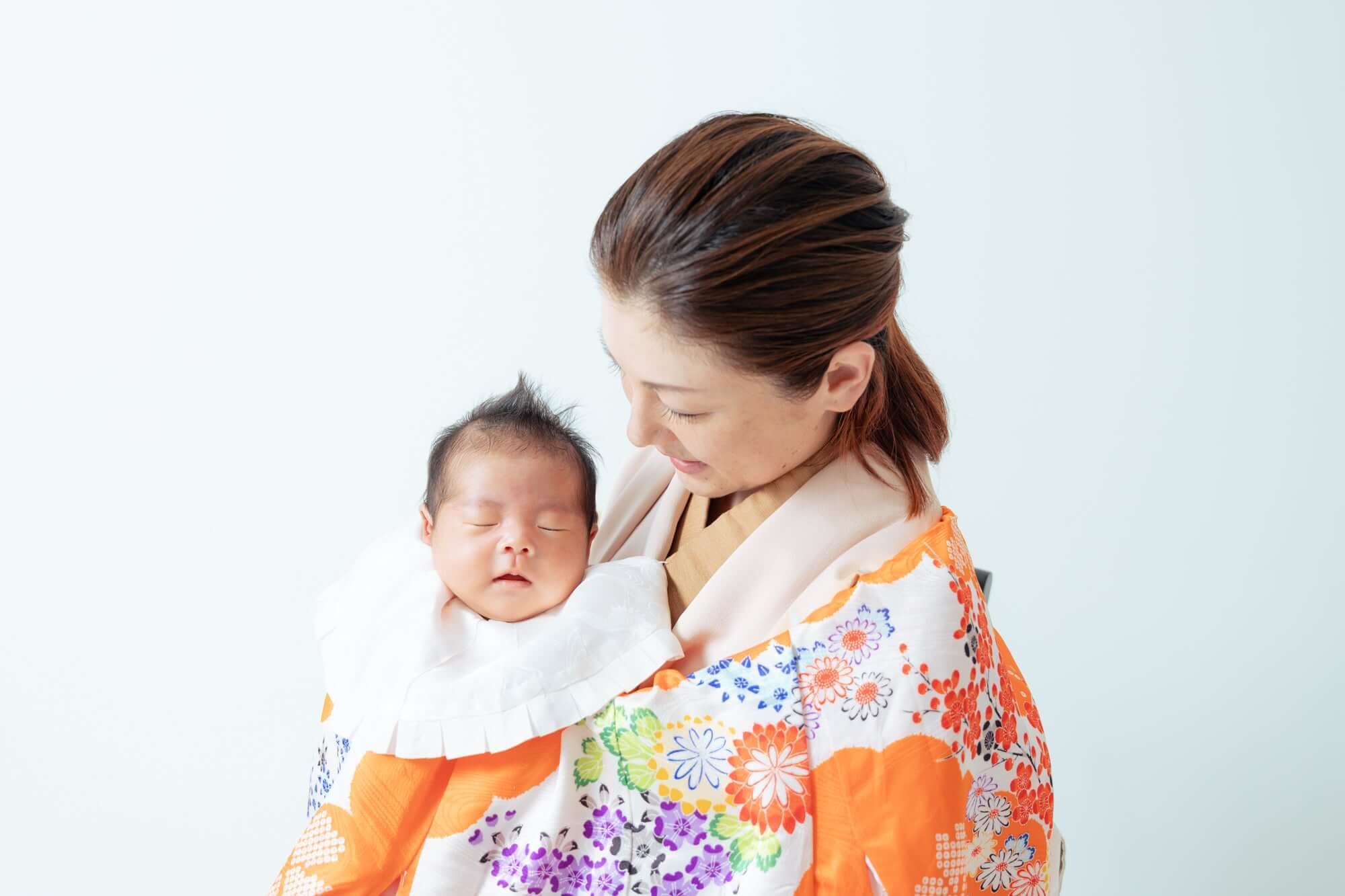 赤ちゃんとのお宮参りの瞬間。フラワーパターンの着物を着た母親が赤ちゃんを抱いているシーン。