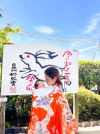 母親が赤ちゃんを抱き、伝統的な着物を着て神社の前でお宮参りの様子を撮影。フォトウエディング北九州。