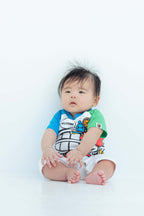 1歳の子供がカラフルな服を着て座っているフォト撮影シーン。