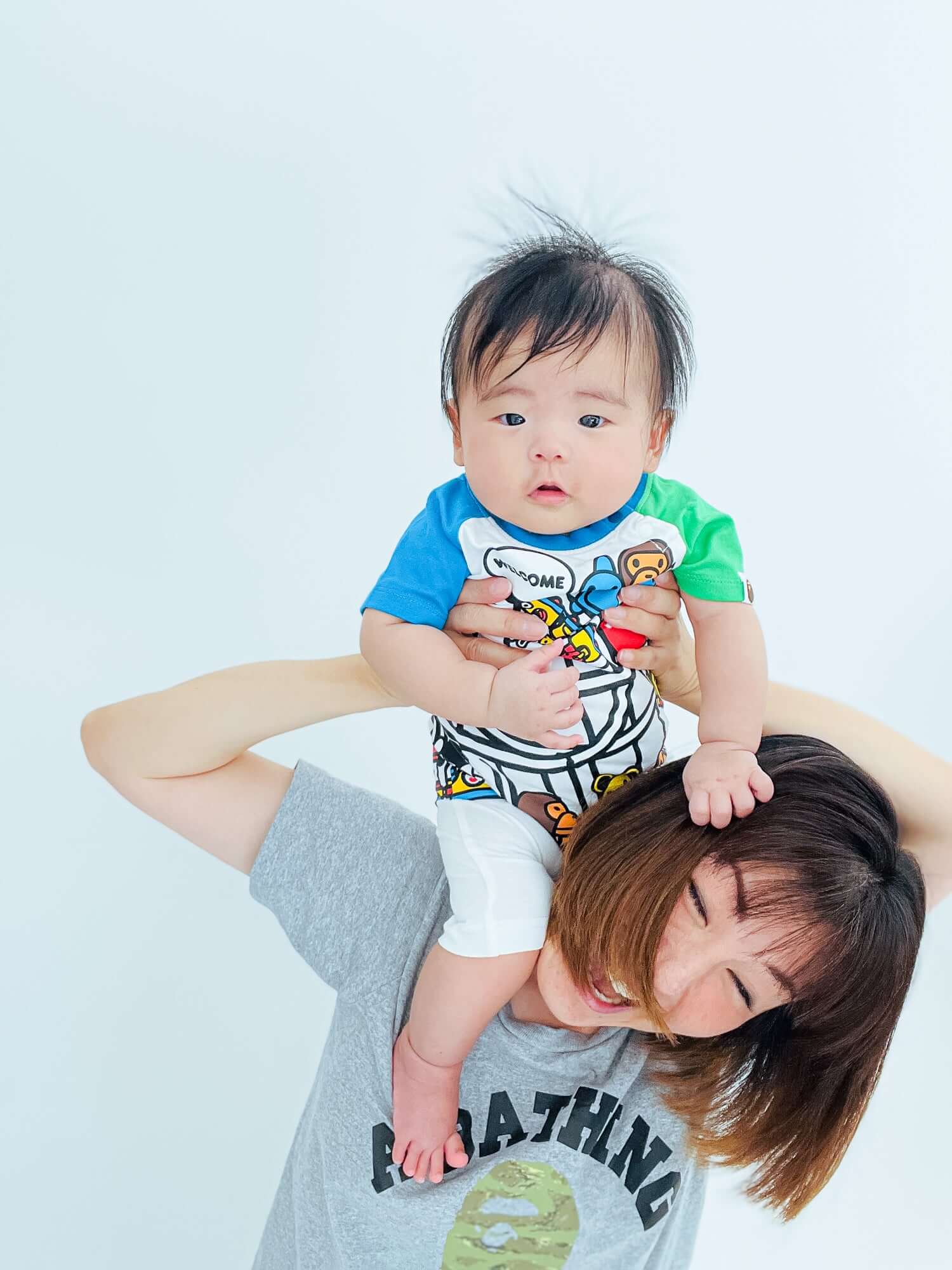 親子コーデの写真、ママが子供を肩に乗せて笑顔で楽しむデザイン。